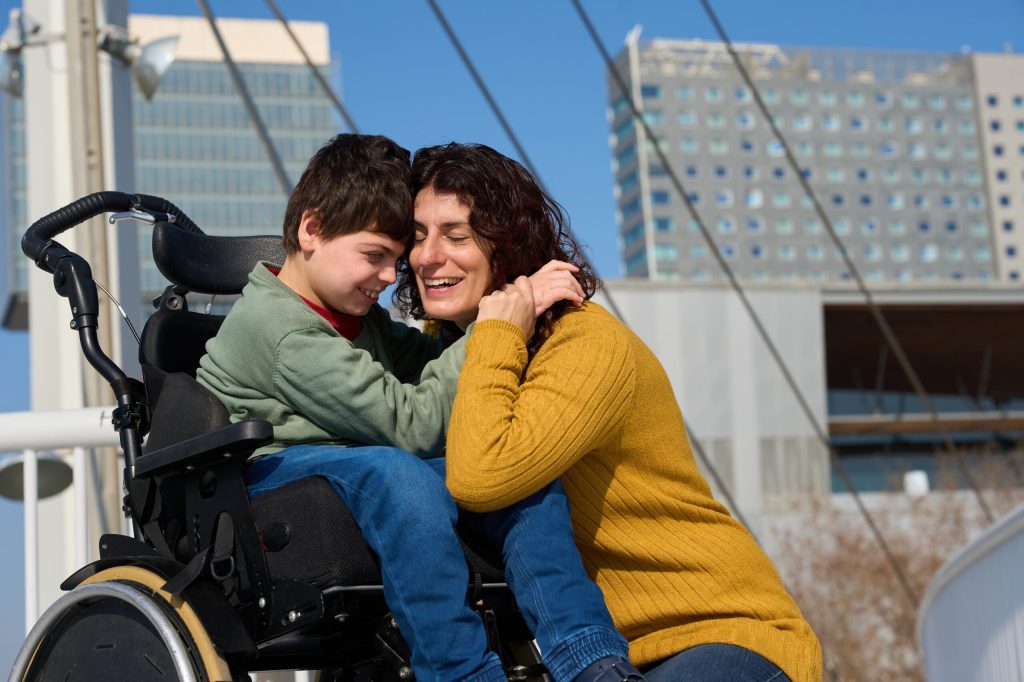 Happy,Mother,Hugging,Her,Son,With,Cerebral,Palsy,In,Wheelchair